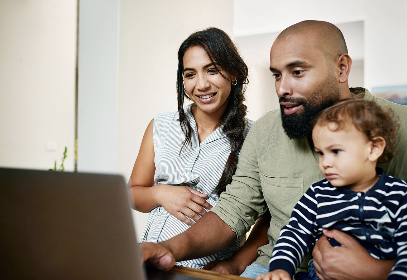 pregnant woman with husband and son looking at laptop