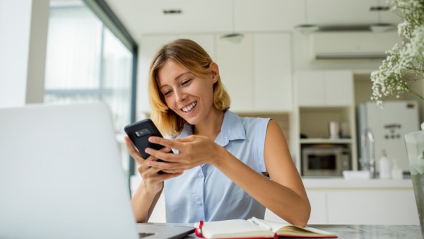 Woman smiling looking at phone and working from home