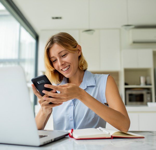 Smiling woman looking at phone and working from home