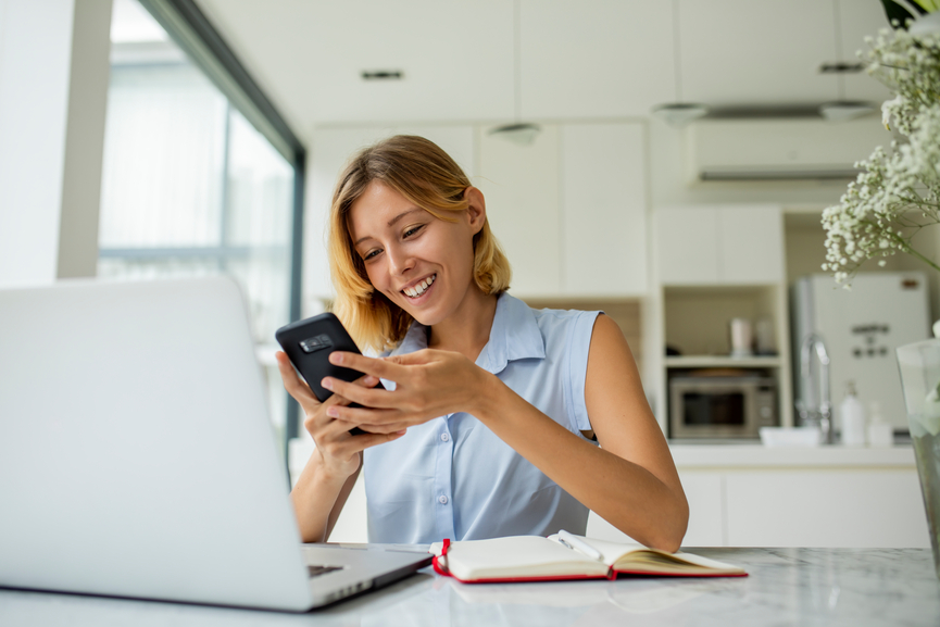 Woman smiling looking at phone and working from home