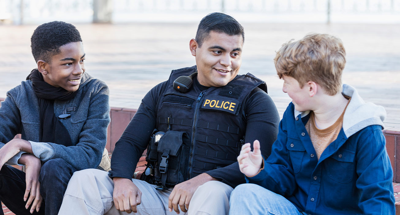 A police officer and two children engage in conversation and smile, suggesting he has one of the most fulfilling jobs.