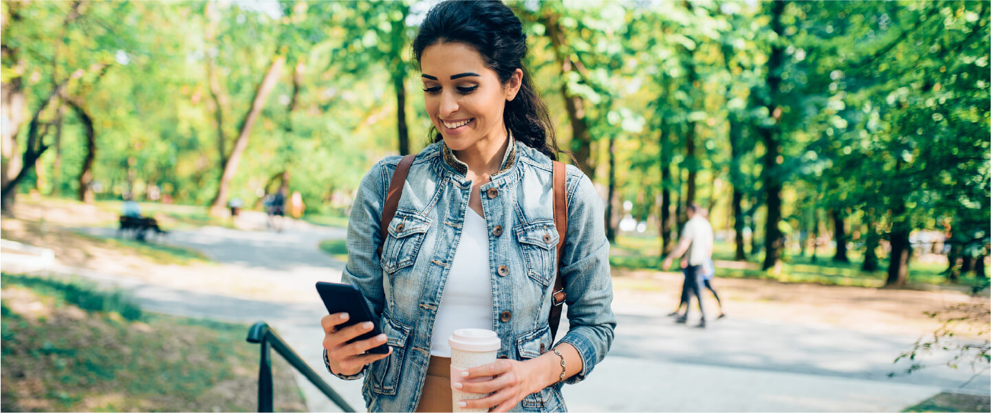 A woman walks through the park as she explores some of the best investing apps for beginners she could potentially download.