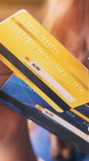 A woman holds three credit cards and decides whether she’d like to choose a secured vs. unsecured credit card.